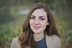 Close-up portrait of a smiling woman with freckles and long hair in a Budapest park during fall.